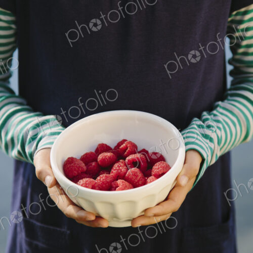 Nine year old girl holding bowl of organic raspberries Nine year old girl holding bowl of organic raspberries
