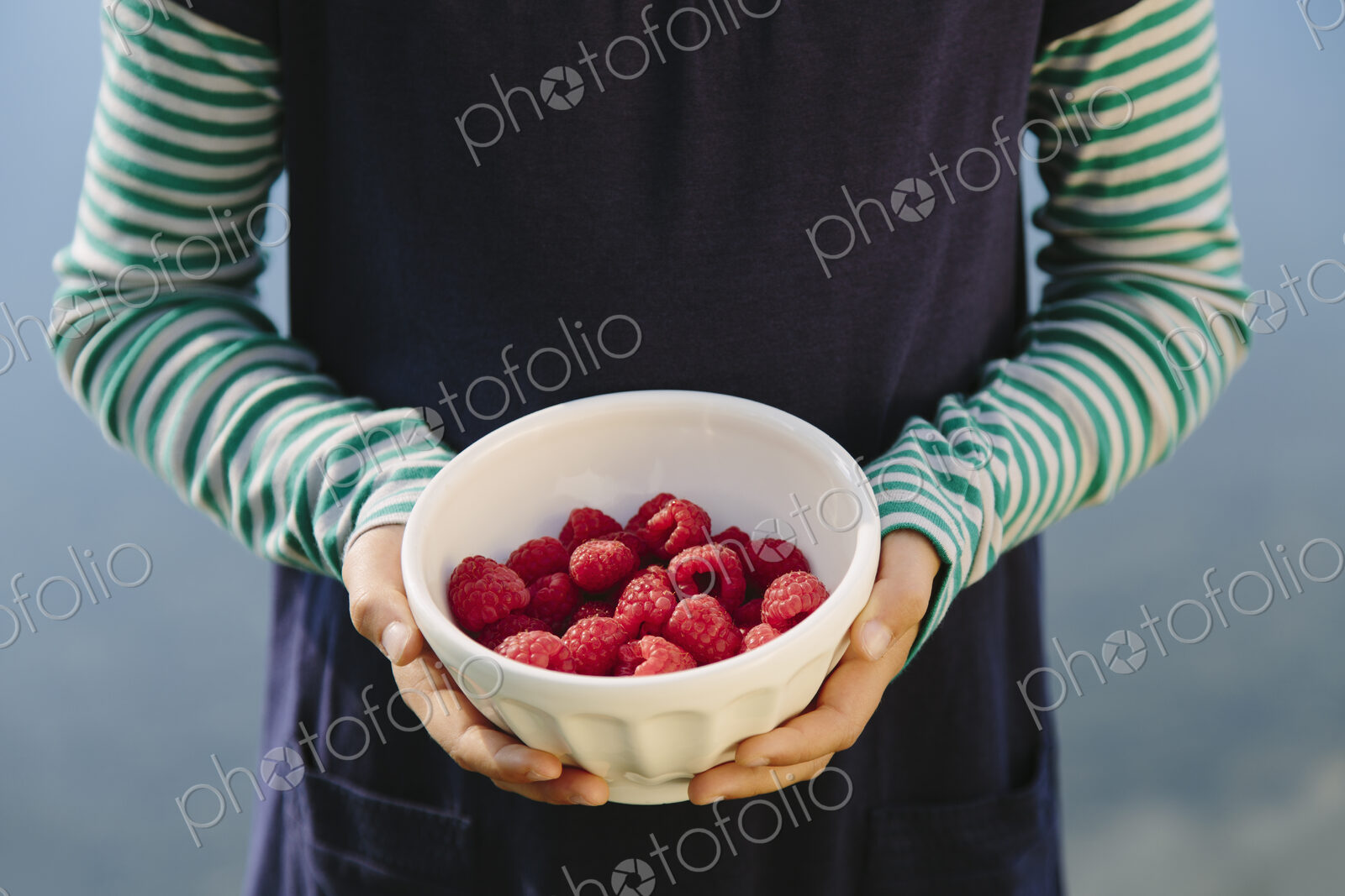 Nine year old girl holding bowl of organic raspberries
