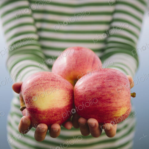 Nine year old girl holding handful of organic apples Nine year old girl holding handful of organic apples