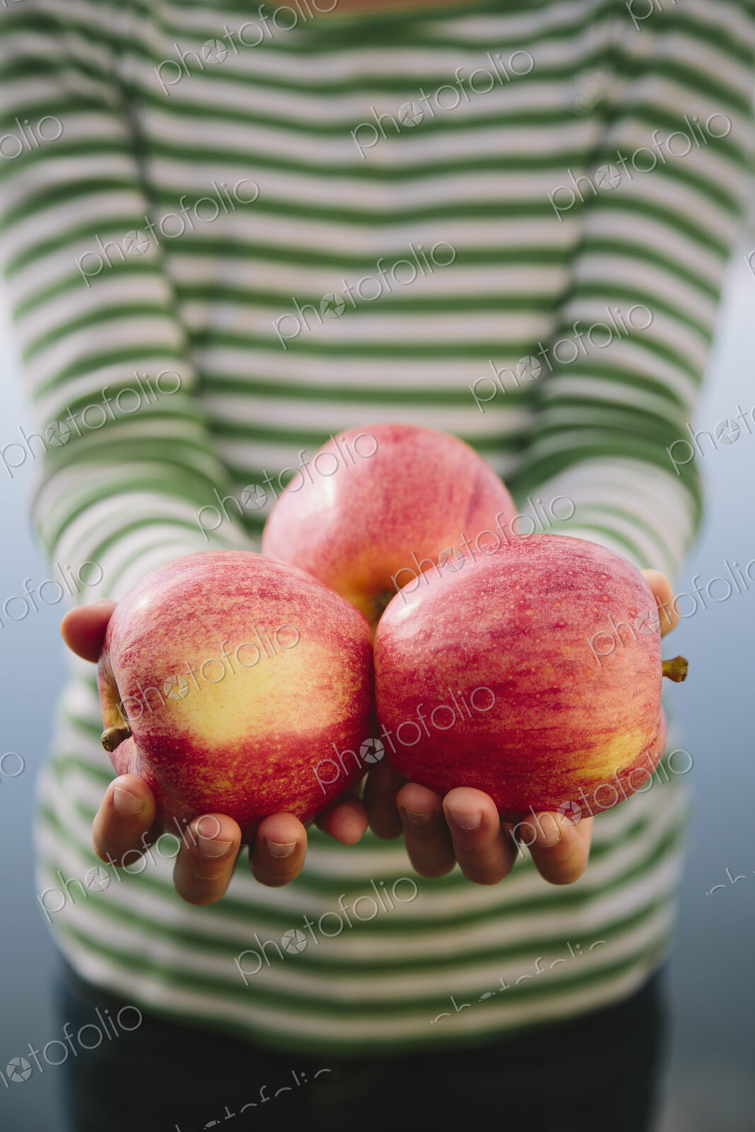 Nine year old girl holding handful of organic apples