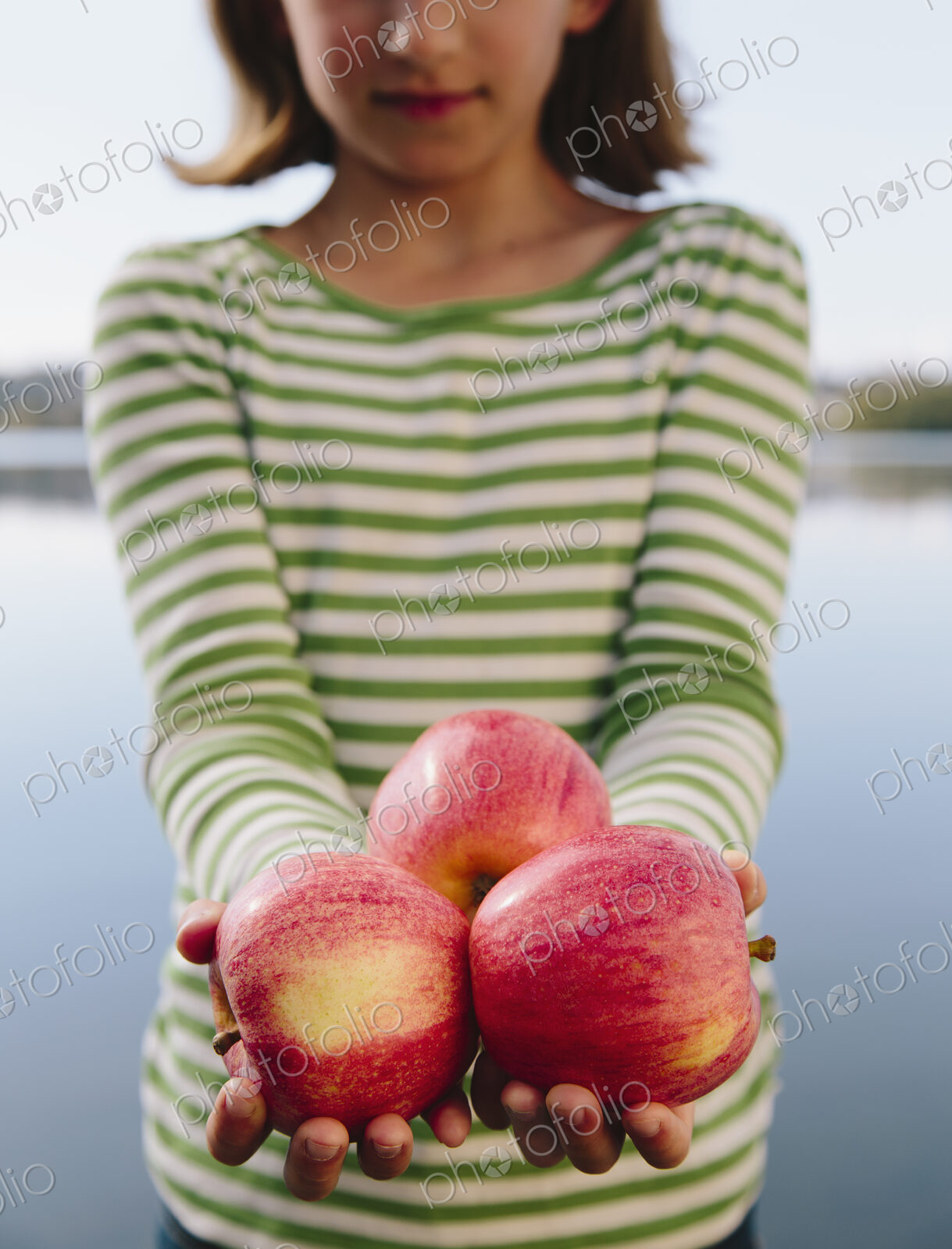 Nine year old girl holding handful of organic apples