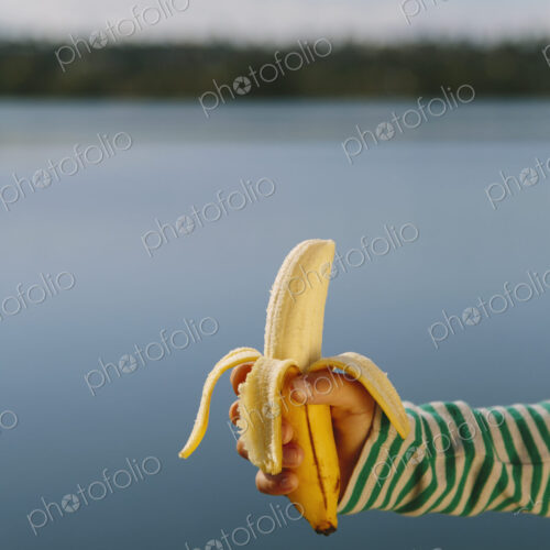 Nine year old girl holding organic, peeled banana Nine year old girl holding organic, peeled banana