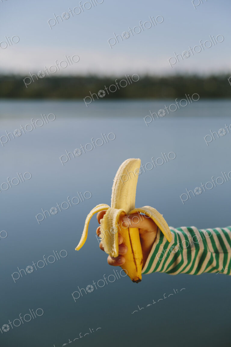 Nine year old girl holding organic, peeled banana