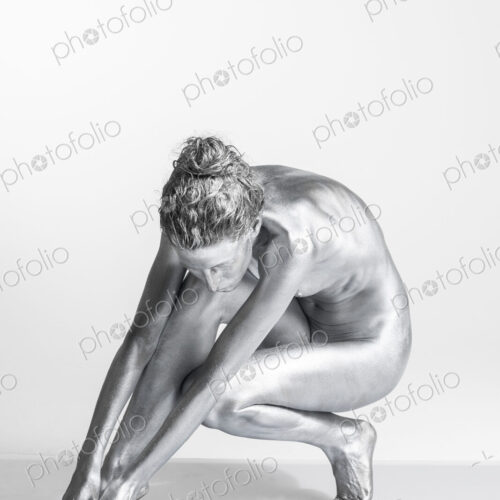 Nude Caucasian woman with silver body paint crouching Nude Caucasian woman with silver body paint crouching