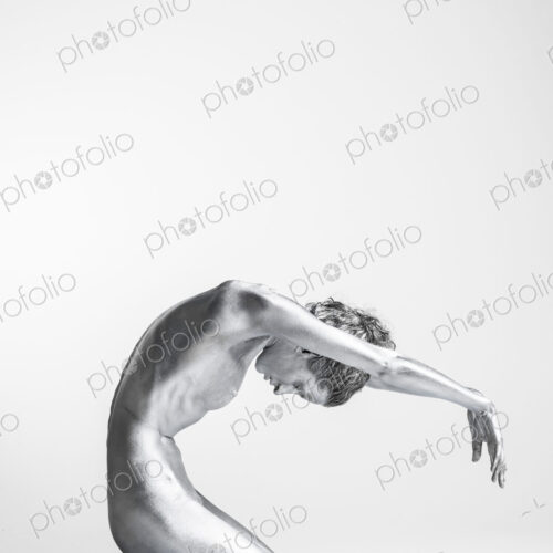 Nude Caucasian woman with silver body paint kneeling, arms forward and head bowed Nude Caucasian woman with silver body paint kneeling, arms forward and head bowed