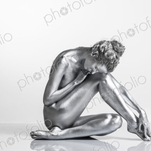 Nude Caucasian woman with silver body paint sitting Nude Caucasian woman with silver body paint sitting