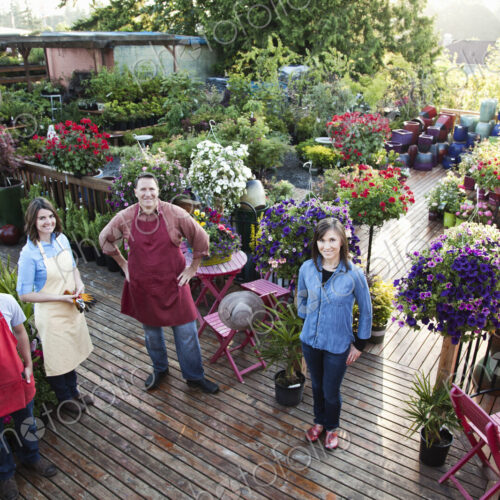 Nursery store owners and employees standing next to plants.
