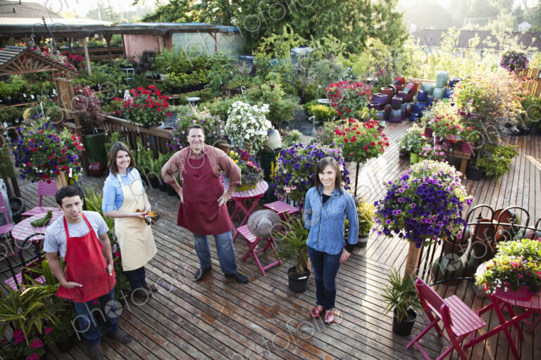 Nursery store owners and employees standing next to plants.