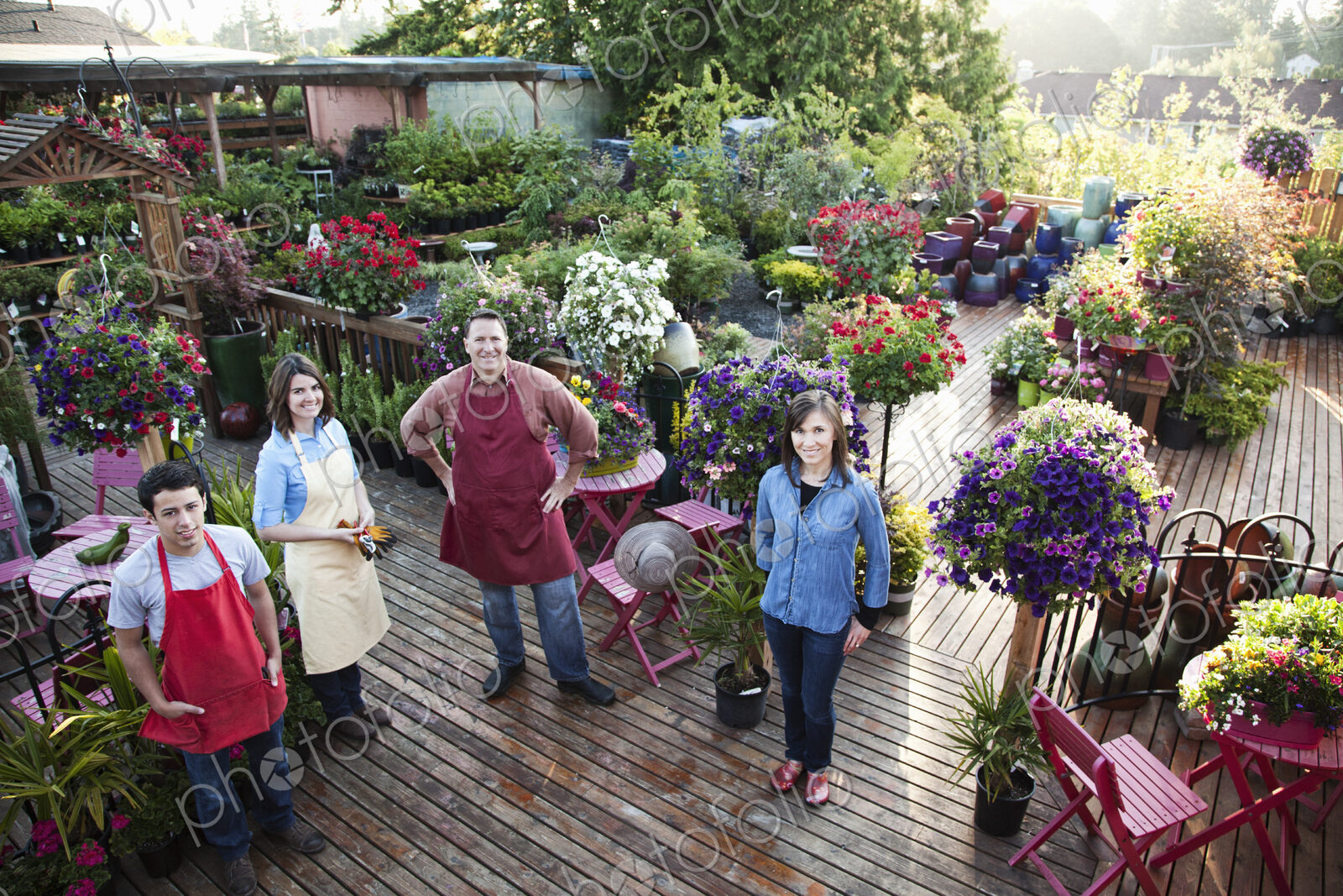 Nursery store owners and employees standing next to plants.