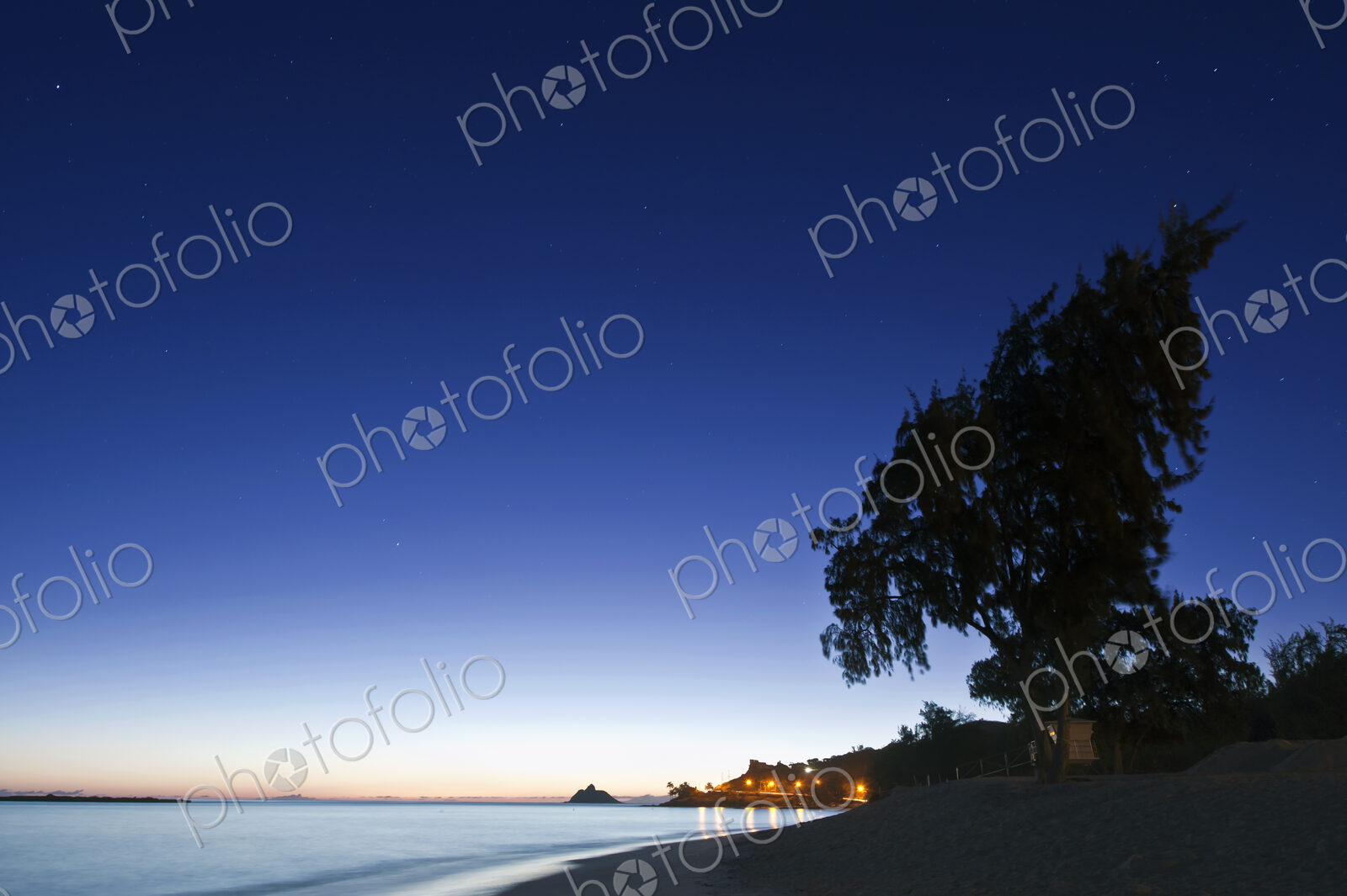 Oahu, Lanikai Beach at dawn, lightening sky on the horizon, beach and palm trees.