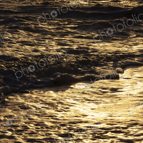 Ocean waves breaking on the shore at sunset, light reflecting off the water. Ocean waves breaking on the shore at sunset, light reflecting off the water.