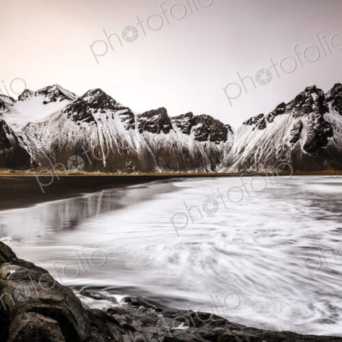 Ocean waves on beach under snowy mountains Ocean waves on beach under snowy mountains