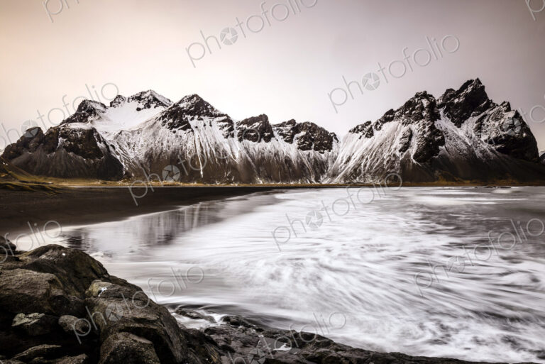 Ocean waves on beach under snowy mountains