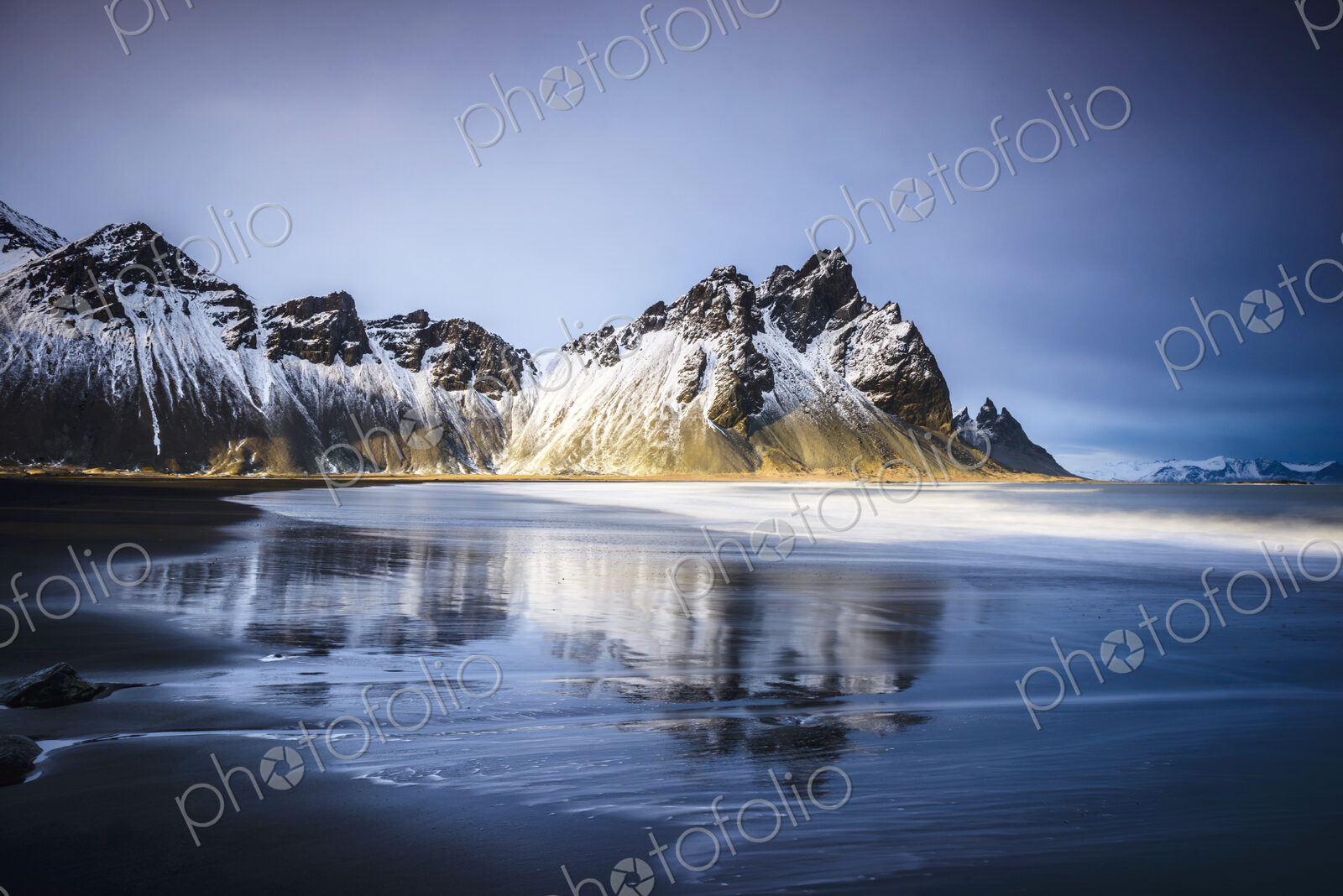 Ocean waves on beach under snowy mountains