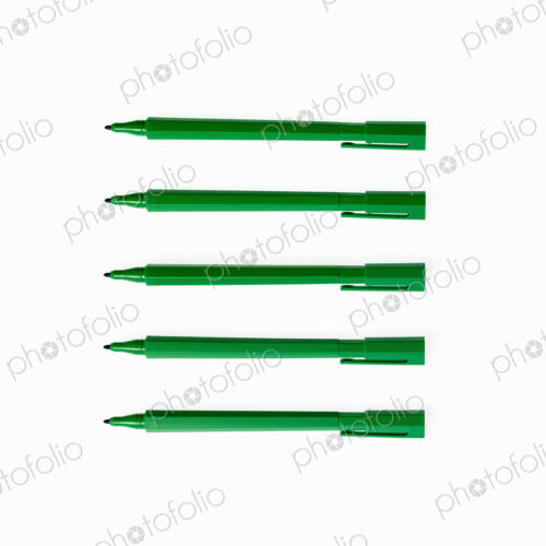 Office supplies. Green coloured pens, felt nibs and pen top cases, arranged in a row. Office supplies. Green coloured pens, felt nibs and pen top cases, arranged in a row.