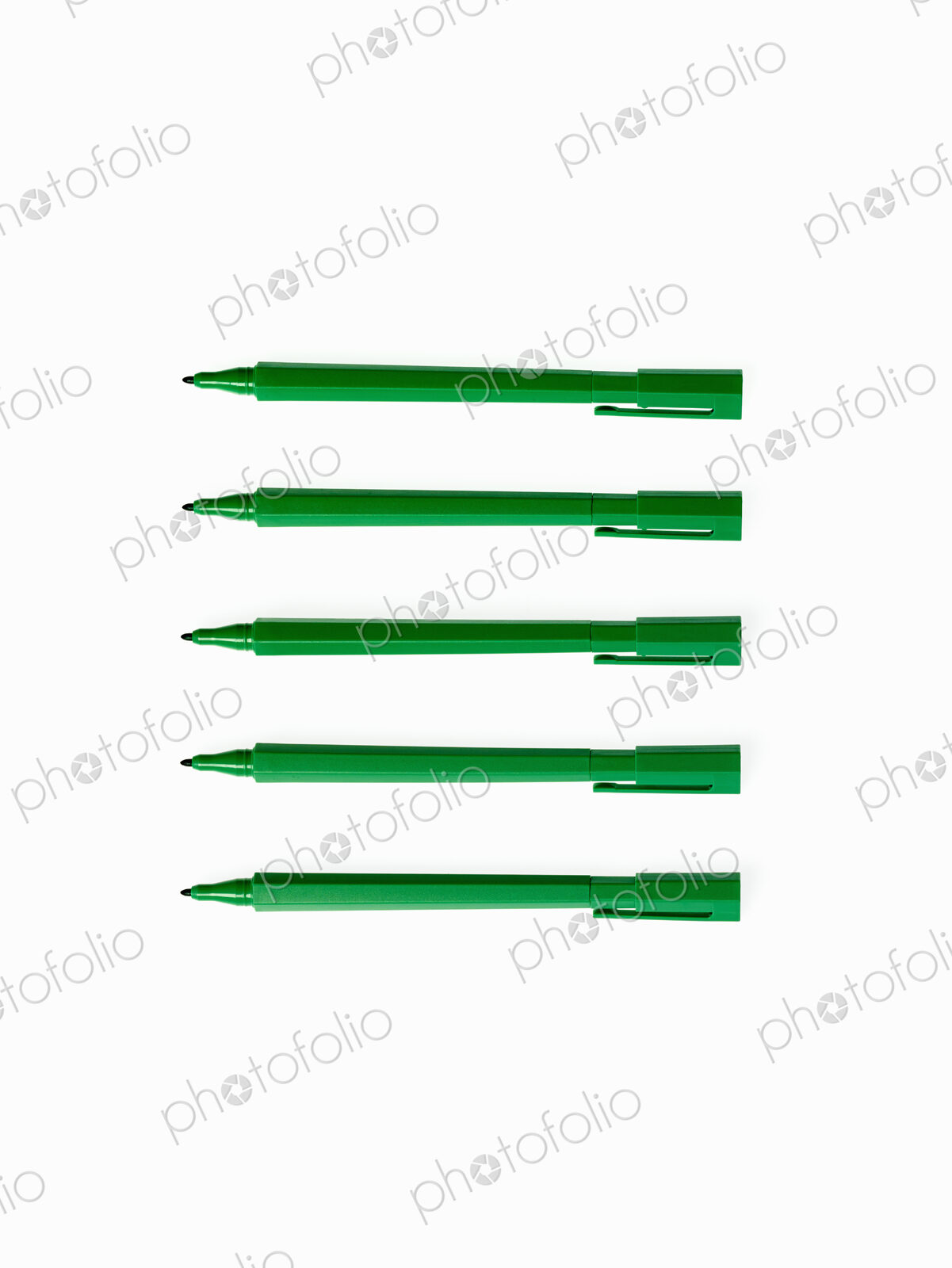 Office supplies. Green coloured pens, felt nibs and pen top cases, arranged in a row.