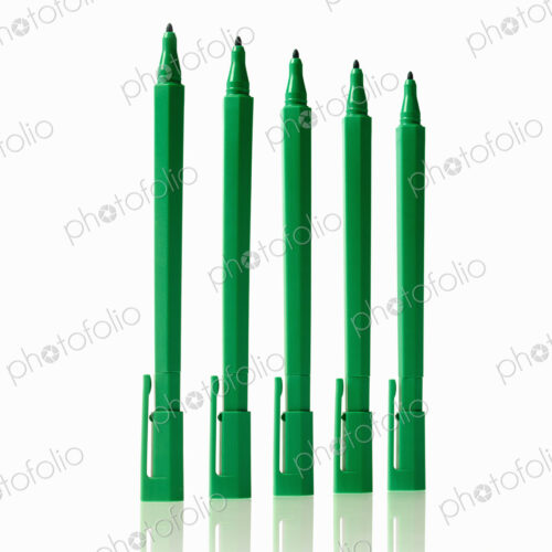 Office supplies. Green coloured pens, felt nibs and pen top cases, arranged in a row. Office supplies. Green coloured pens, felt nibs and pen top cases, arranged in a row.