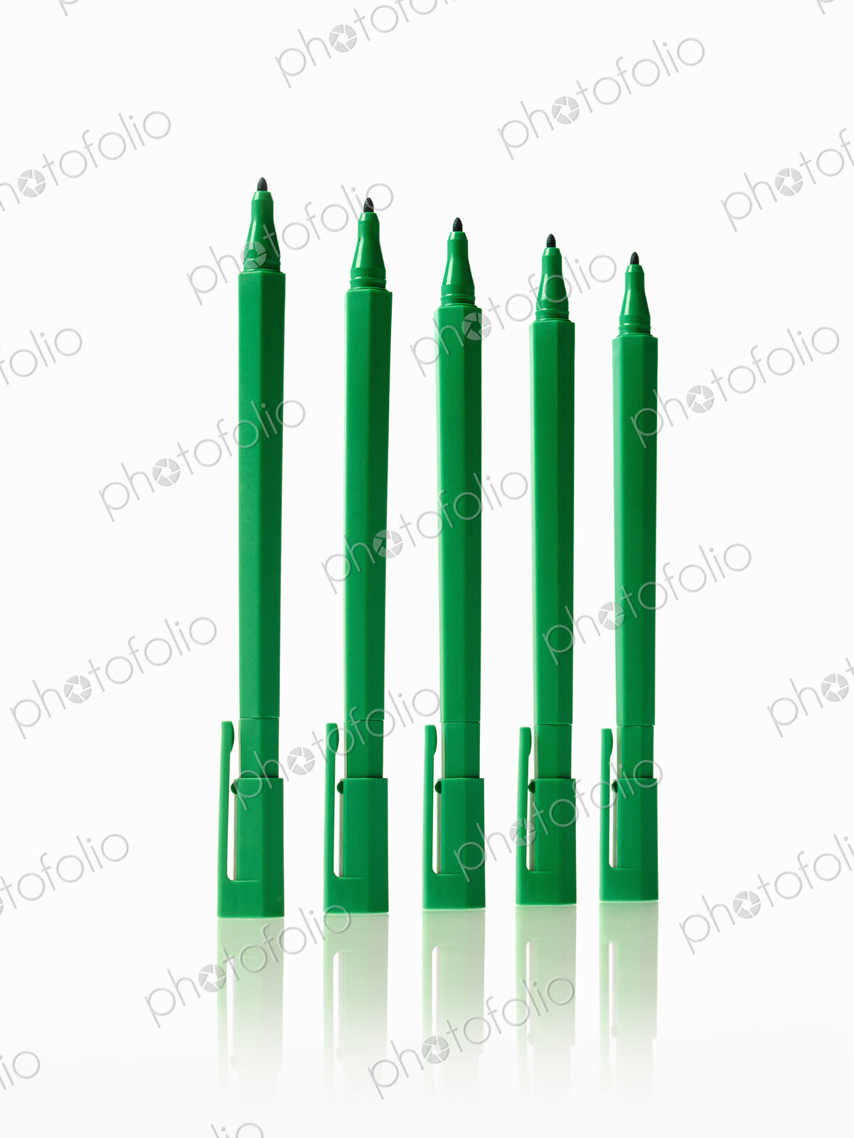 Office supplies. Green coloured pens, felt nibs and pen top cases, arranged in a row.