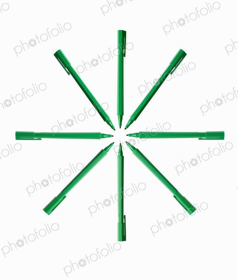 Office supplies. Green coloured pens, felt nibs and pen top cases, arranged in a star…