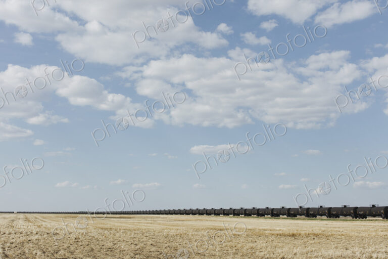 Oil train cars and fallow farmland, near Swift Current, Saskatchewan, Canada.