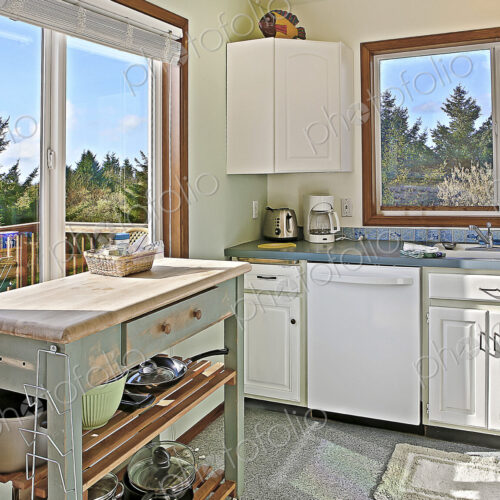 Old fashioned kitchen with views of trees from a deck.