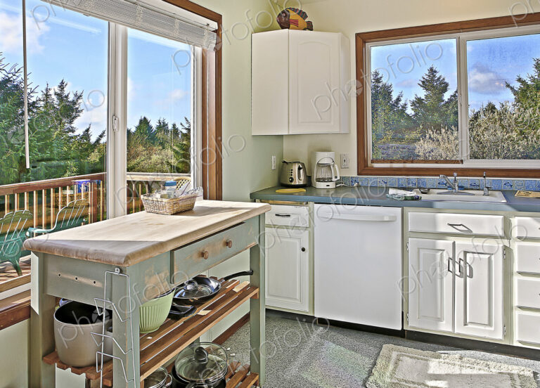 Old fashioned kitchen with views of trees from a deck.