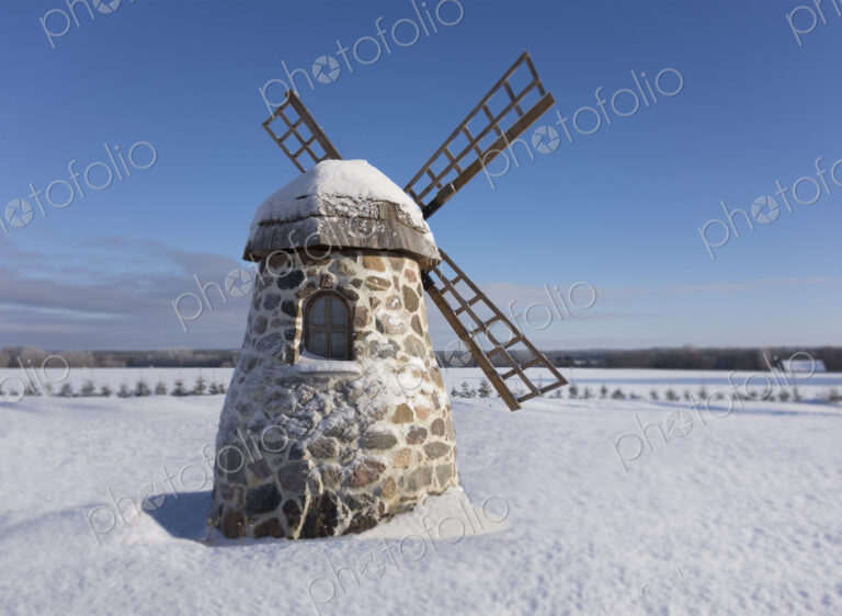 Old stone windmill on snowy landscape at winter.