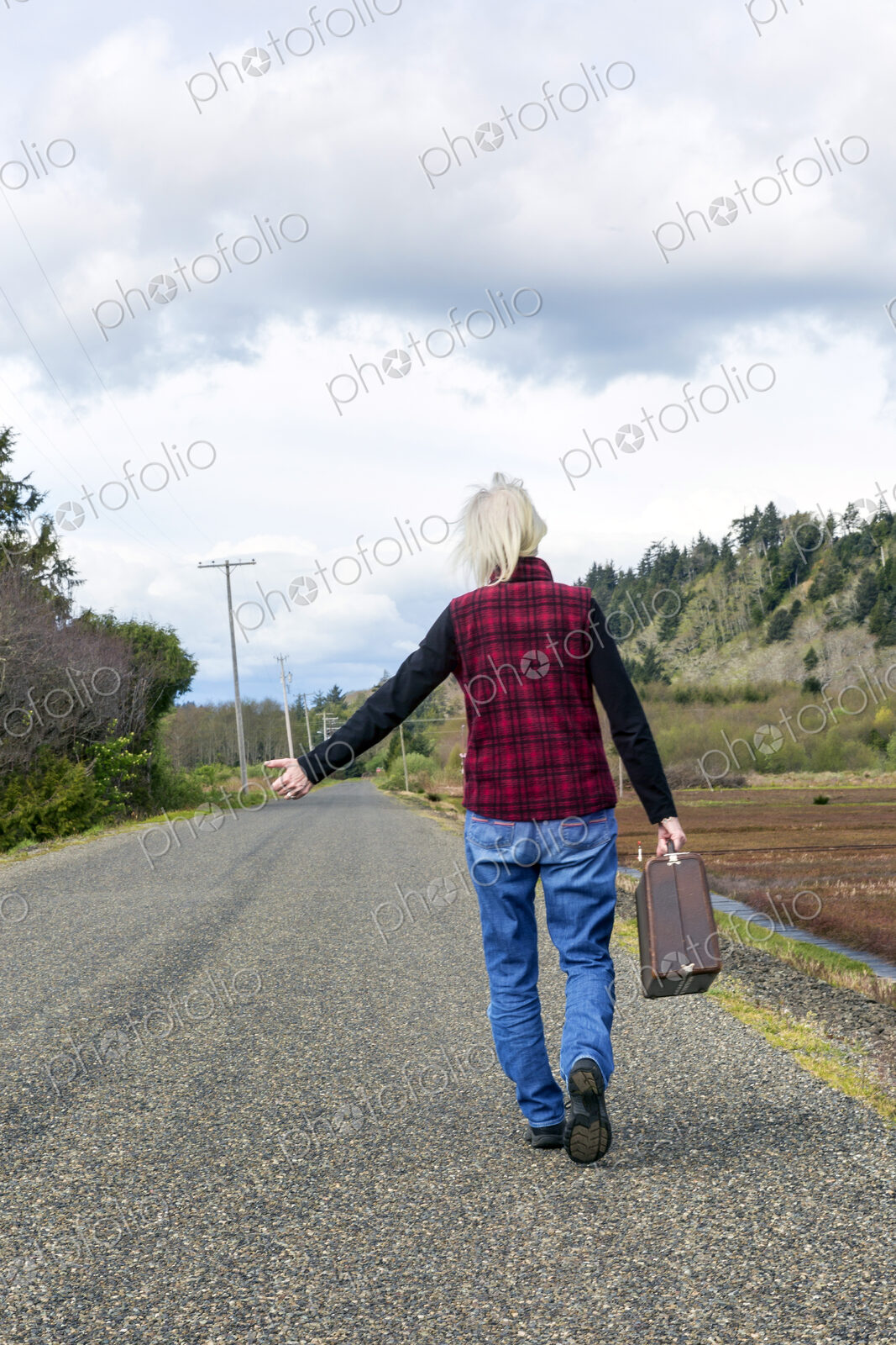 Older woman hitch hiking on rural road