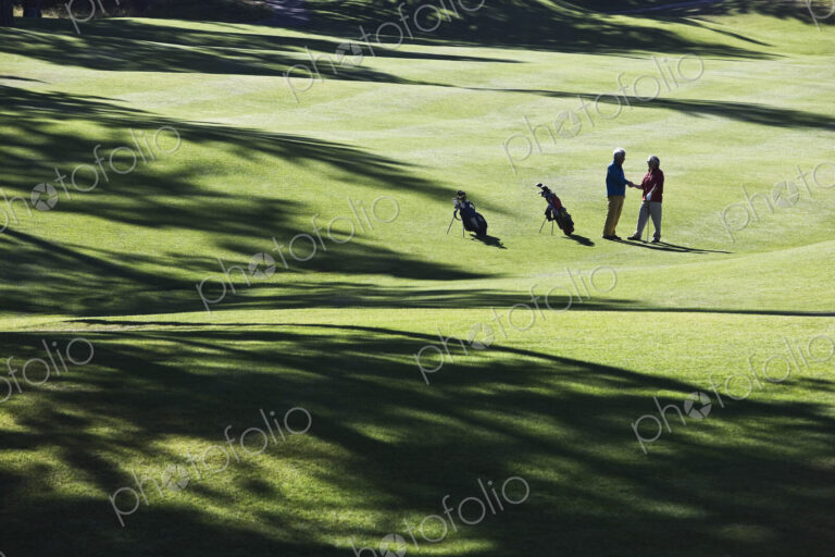 One golfer shking hands with another after making a great golf shot.