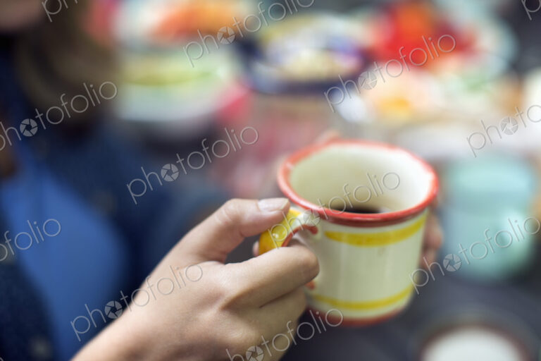 One person at a picnic table outdoors, holding a china mug.