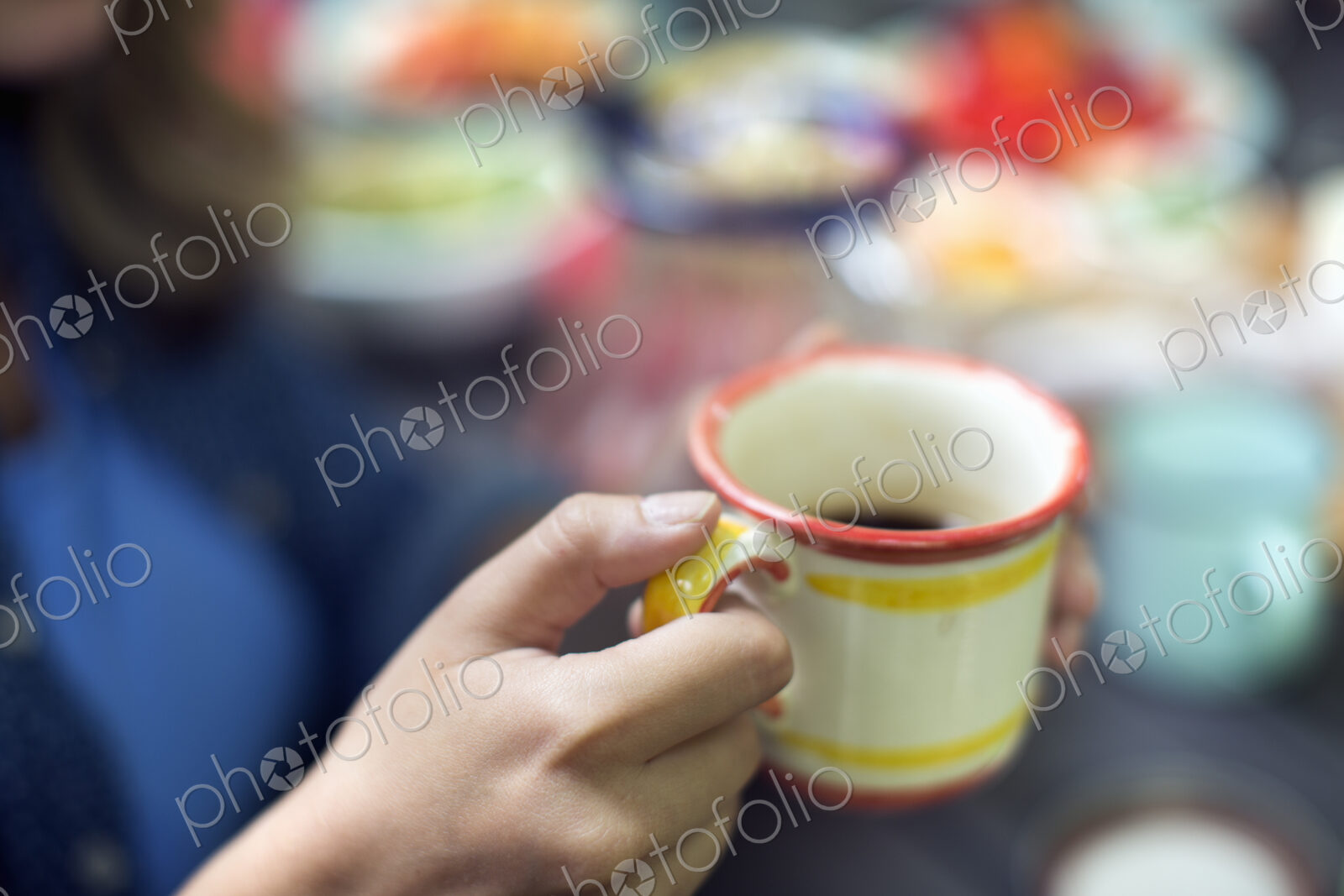 One person at a picnic table outdoors, holding a china mug.