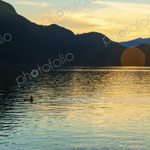 One person kayaking at sunset in Howe Sound near Porteau Cove. One person kayaking at sunset in Howe Sound near Porteau Cove.