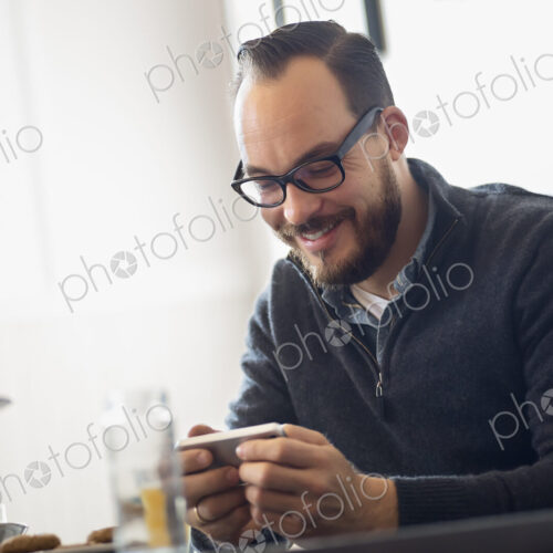 One person sitting at a table in a coffeeshop. A bearded man having a drink of coffee.