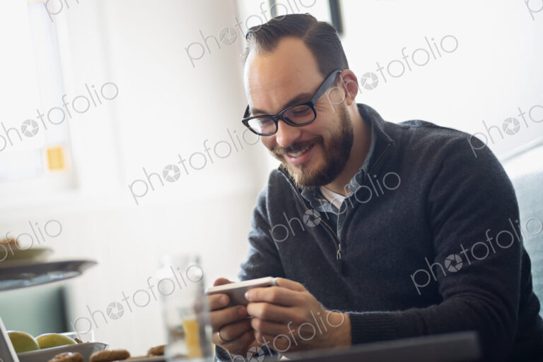 One person sitting at a table in a coffeeshop. A bearded man having a drink of coffee.