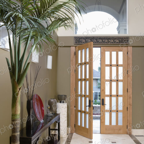 Open door to hallway with potted plant and console table.
