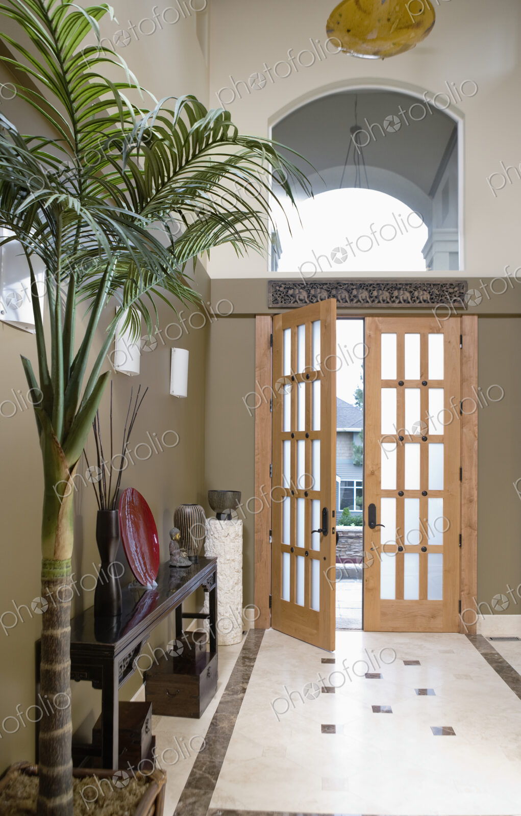 Open door to hallway with potted plant and console table.