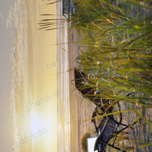 Open laptop on sun lounger in reeds on at beach at sunset. Open laptop on sun lounger in reeds on at beach at sunset.