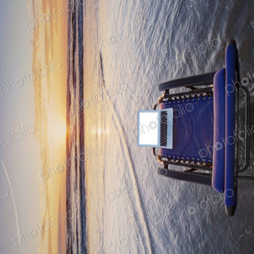 Open laptop on sun lounger in shallow wave at beach at sunset. Open laptop on sun lounger in shallow wave at beach at sunset.