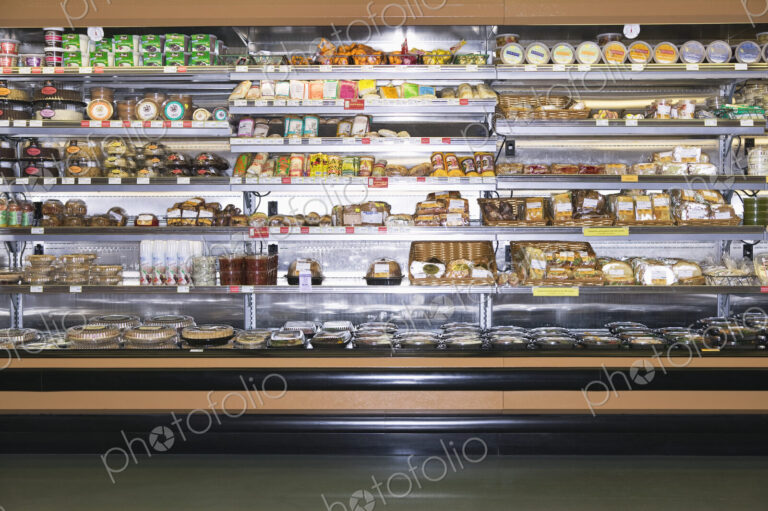 Open refridgerator stocked with food in supermarket.