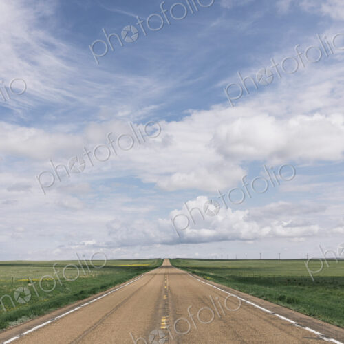 Open road through vast prairie and farmland, Saskatchewan, Canada.