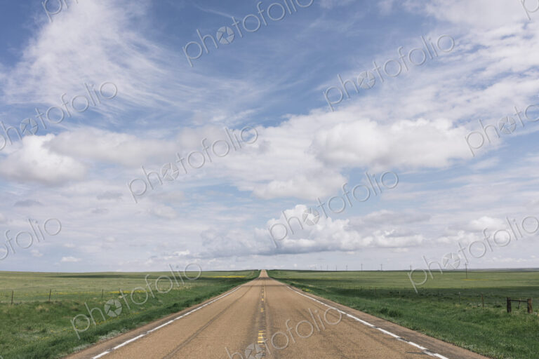 Open road through vast prairie and farmland, Saskatchewan, Canada.