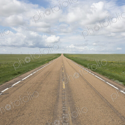 Open road through vast prairie and farmland, Saskatchewan, Canada.