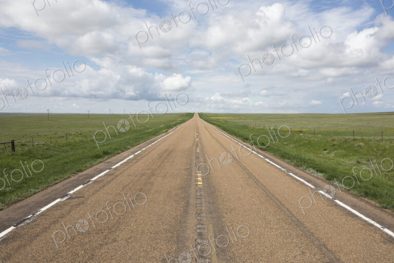 Open road through vast prairie and farmland, Saskatchewan, Canada.