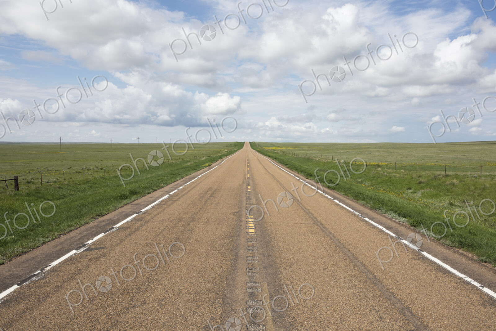 Open road through vast prairie and farmland, Saskatchewan, Canada.