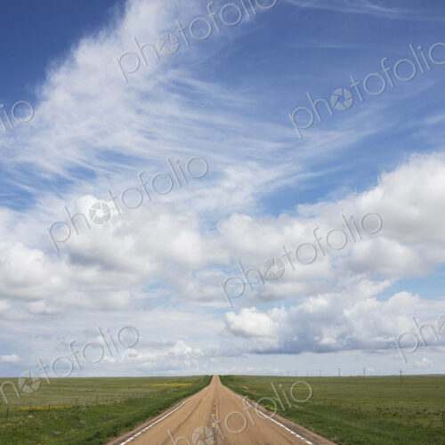 Open road through vast prairie and farmland, Saskatchewan, Canada.