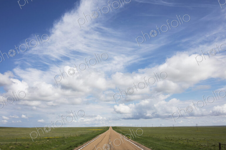 Open road through vast prairie and farmland, Saskatchewan, Canada.