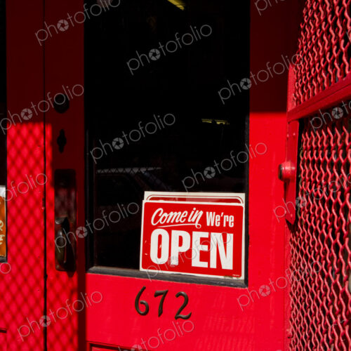 Open sign on red wooden door, a business or shop.