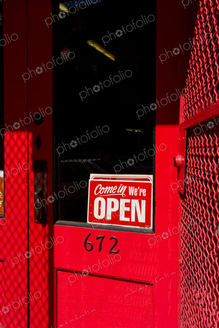 Open sign on red wooden door, a business or shop.