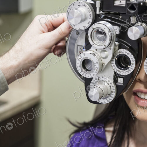 Ophthalmologist using a phoropter instrument to adjust an eyeglass perspection for a… Ophthalmologist using a phoropter instrument to adjust an eyeglass perspection for a…