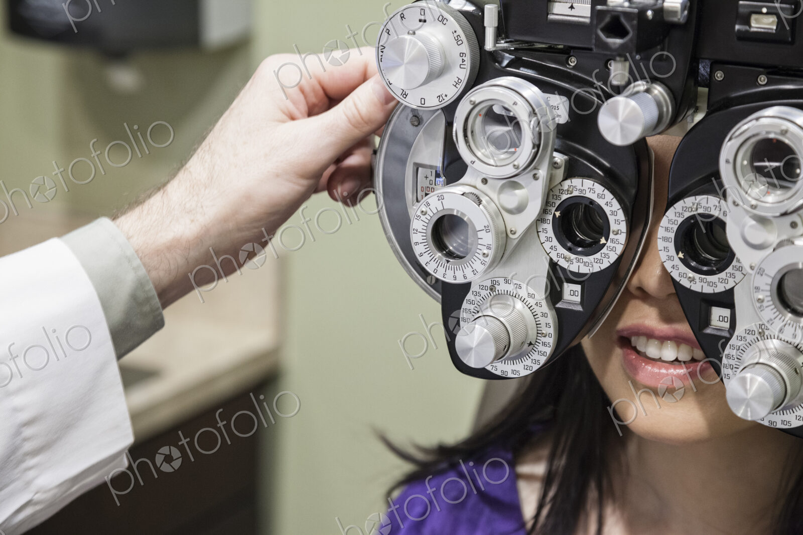 Ophthalmologist using a phoropter instrument to adjust an eyeglass perspection for a…